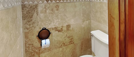 A bathroom with a toilet, a towel rack, and a shower area.