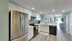 Une cuisine moderne dotée d’appareils électroménagers en acier inoxydable, de meubles blancs et d’un plancher en bois.