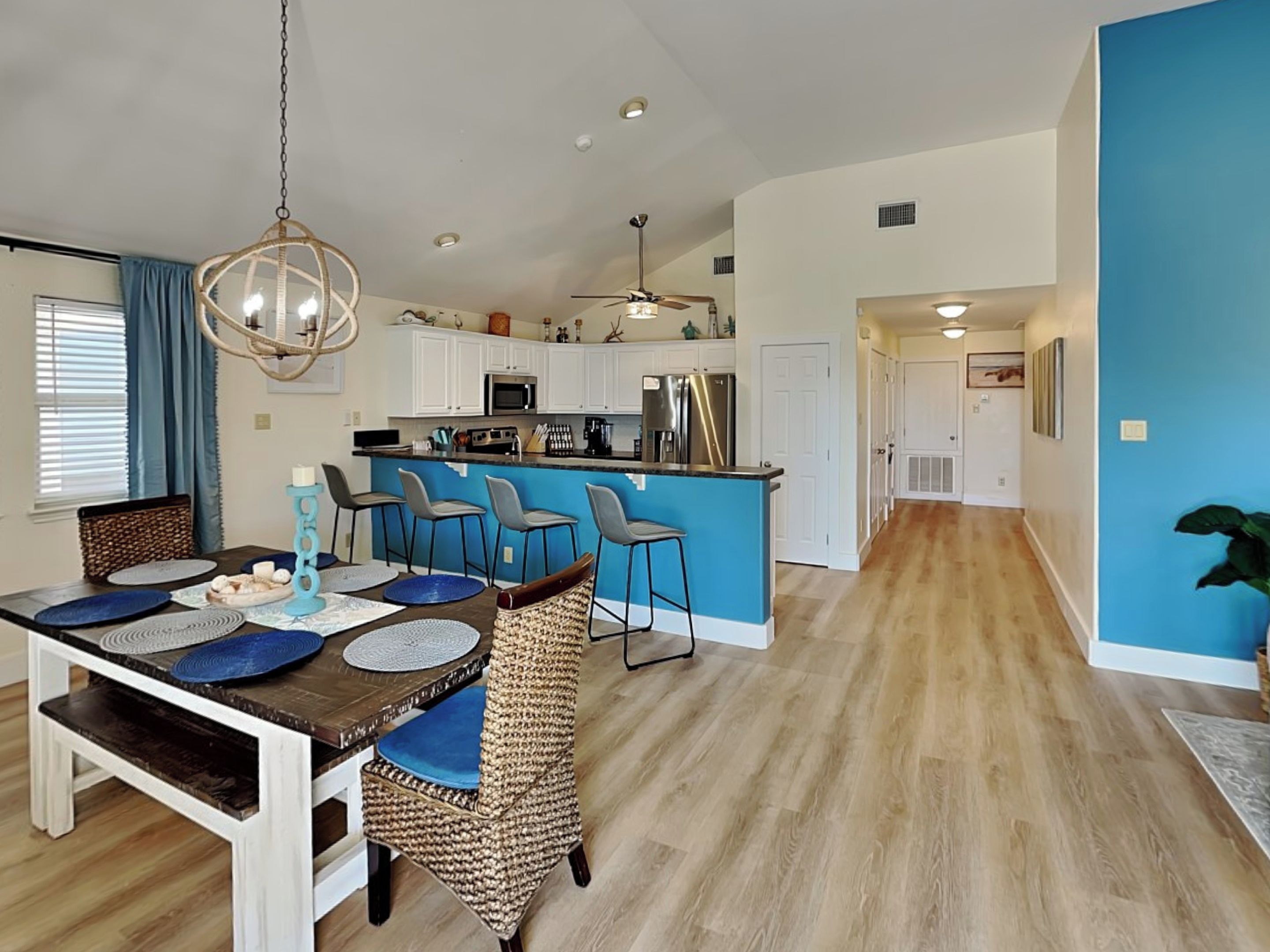 A modern kitchen with white cabinets, a blue island, and stainless steel appliances.