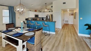 A modern kitchen with white cabinets, a blue island, and stainless steel appliances.