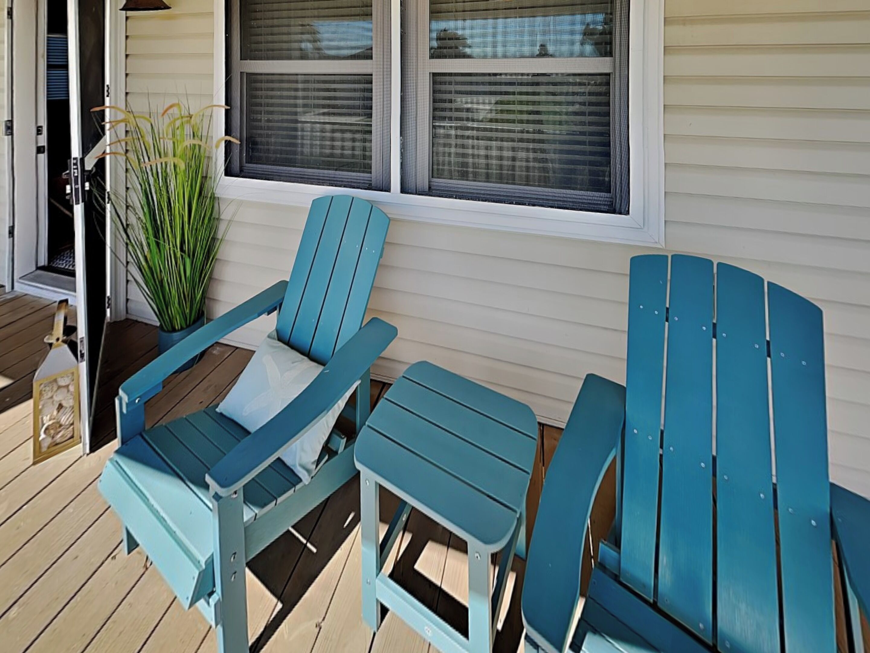 Una terraza con dos sillas Adirondack azules y una mesa a juego.