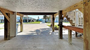 A covered outdoor area with a concrete floor, wooden beams, and a metal railing.