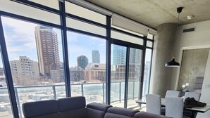 A modern living room with a sectional sofa, two round tables, and large windows offering a city view.