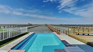 A swimming pool with a wooden deck and white railings, surrounded by a white fence. - The Reel Mccoy by Miss Kitty’s (Rockport)