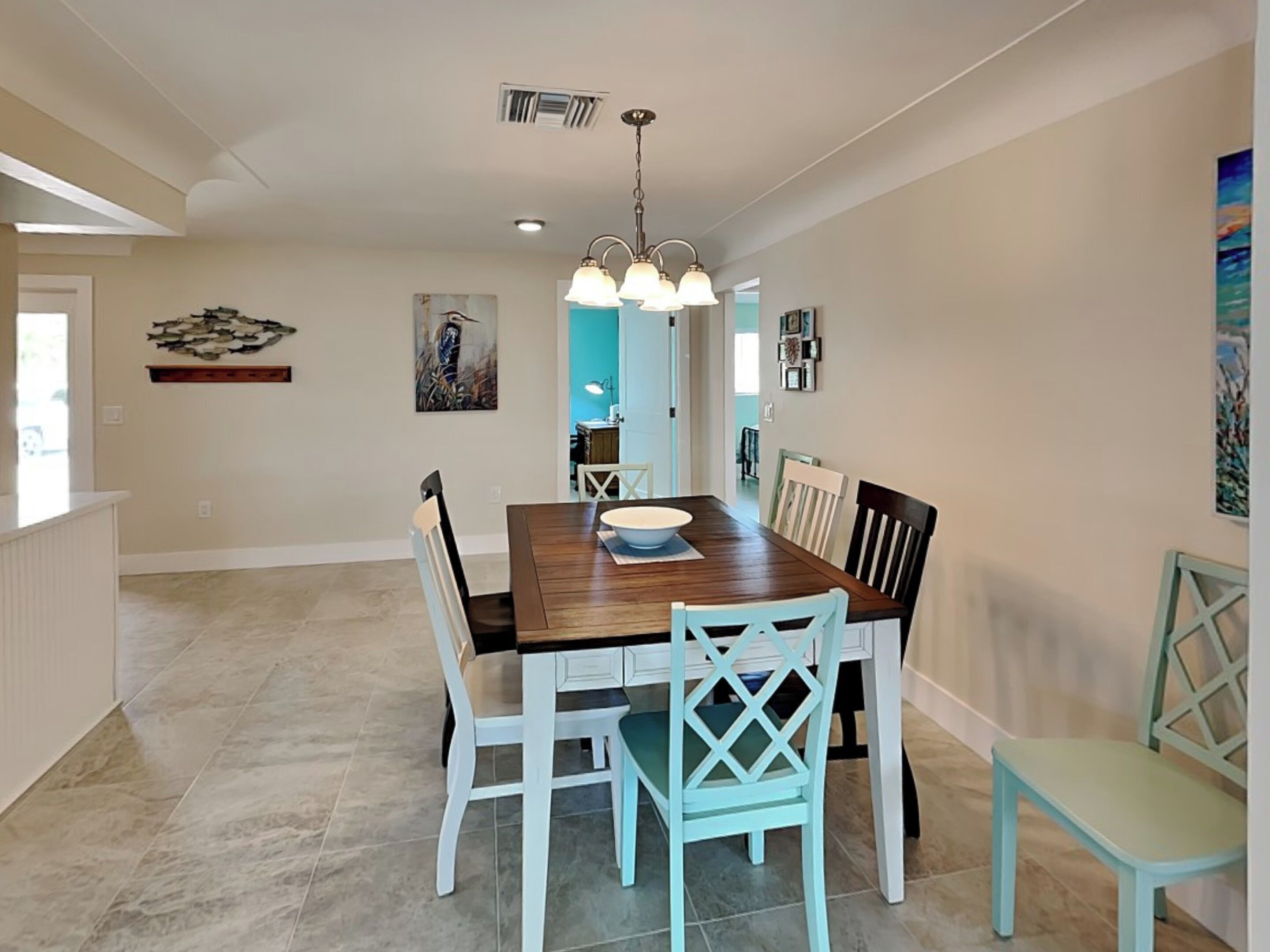 A dining area with a wooden table, white chairs, and a chandelier.