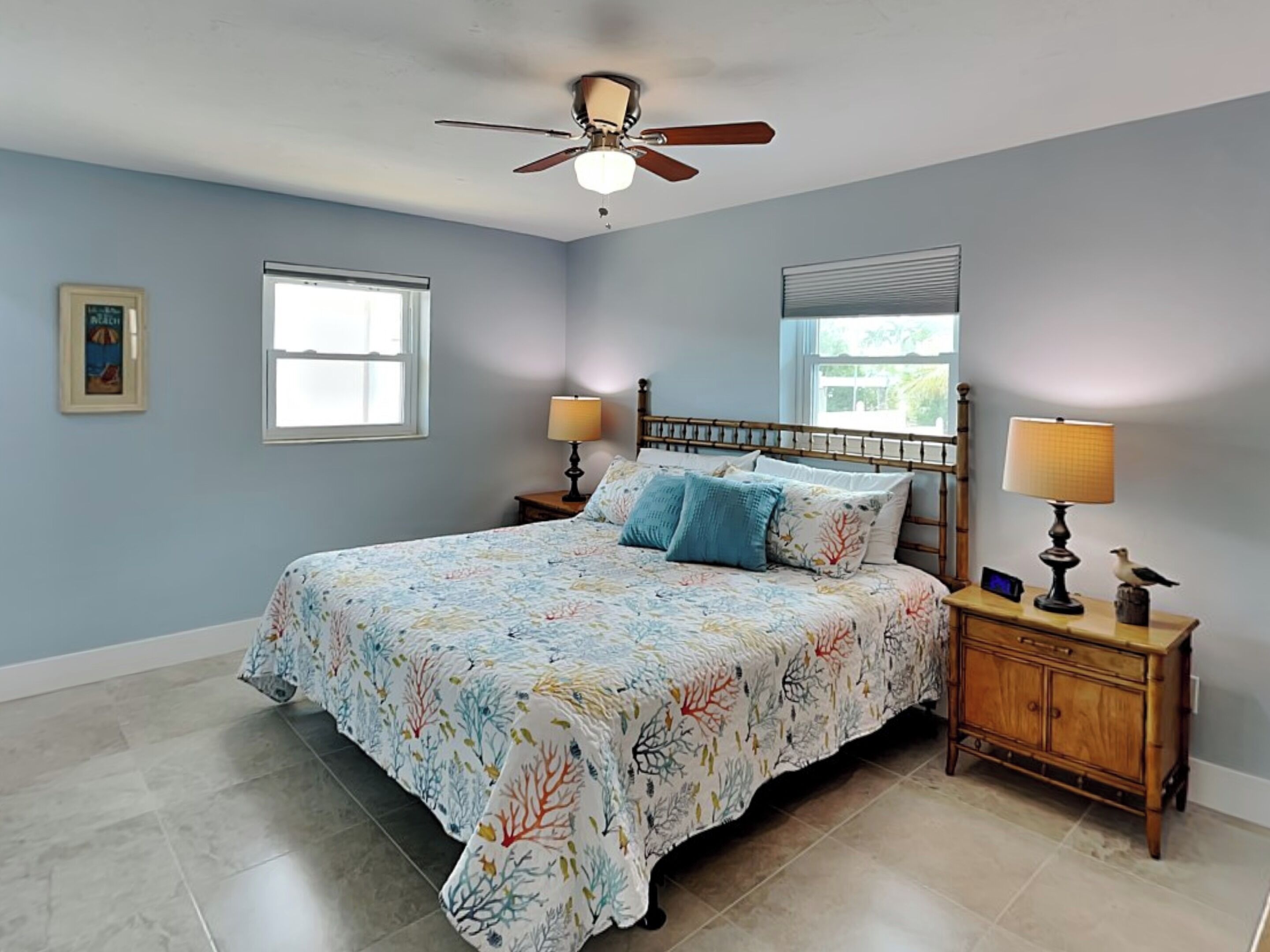 A bedroom with a bed, two bedside tables, a ceiling fan, and a window.
