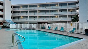 Un hôtel à plusieurs étages doté d’une piscine, d’un espace extérieur aménagé et d’une zone délimitée par une clôture.