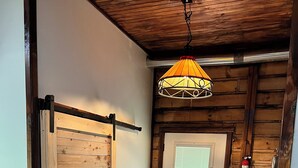 Interior de madera con una puerta corredera, una puerta con ventanal y una lámpara colgante.