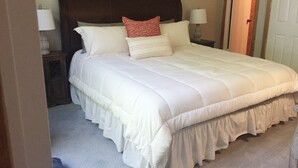 A neatly made bed with white bedding and a ruffled skirt, a dark headboard, two bedside lamps, and a framed picture on the wall. - Prime Location! Ski In, Ski Out 3BDR plus bonus room, 3BA, Condo on Dobie (Wintergreen Resort)