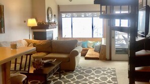 A cozy living room with a fireplace, a dining area, and a staircase leading to an upper level. - Prime Location! Ski In, Ski Out 3BDR plus bonus room, 3BA, Condo on Dobie (Wintergreen Resort)