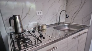 Una cocina con estufa de acero inoxidable, un lavamanos y un salpicadero de mármol.