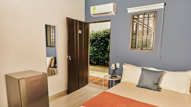 Un dormitorio con cama, mesita de noche, lámpara y una puerta abierta que da a un balcón.