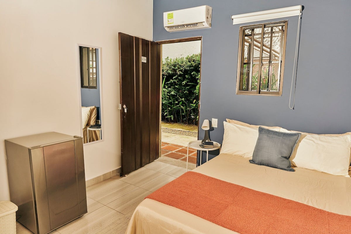 A bedroom with a bed, bedside table, lamp, and an open door leading to a balcony.