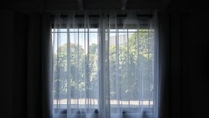 Una habitación con un ventanal cubierto por cortinas translúcidas que dejan entrar luz natural.