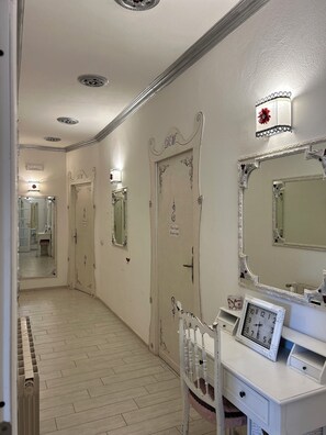 A hallway with ornate doors, a vanity with a mirror and clock, and a radiator.