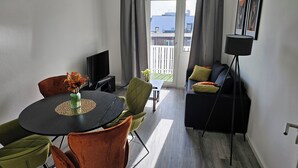Una sala de estar moderna con una mesa de comedor redonda, un sofá y un televisor.