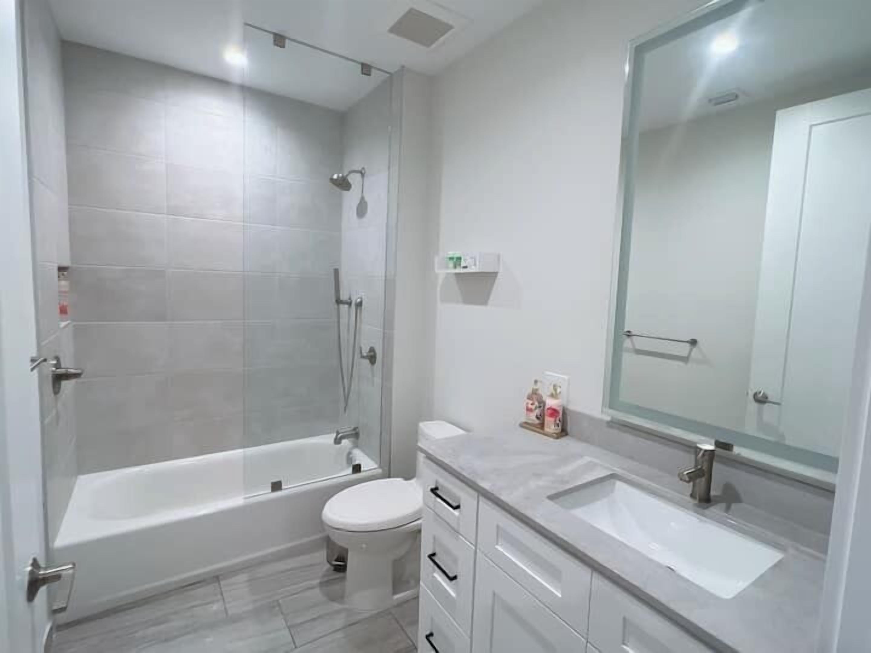 Een moderne badkamer met een inloopdouche, toilet en een wastafel met spiegel.