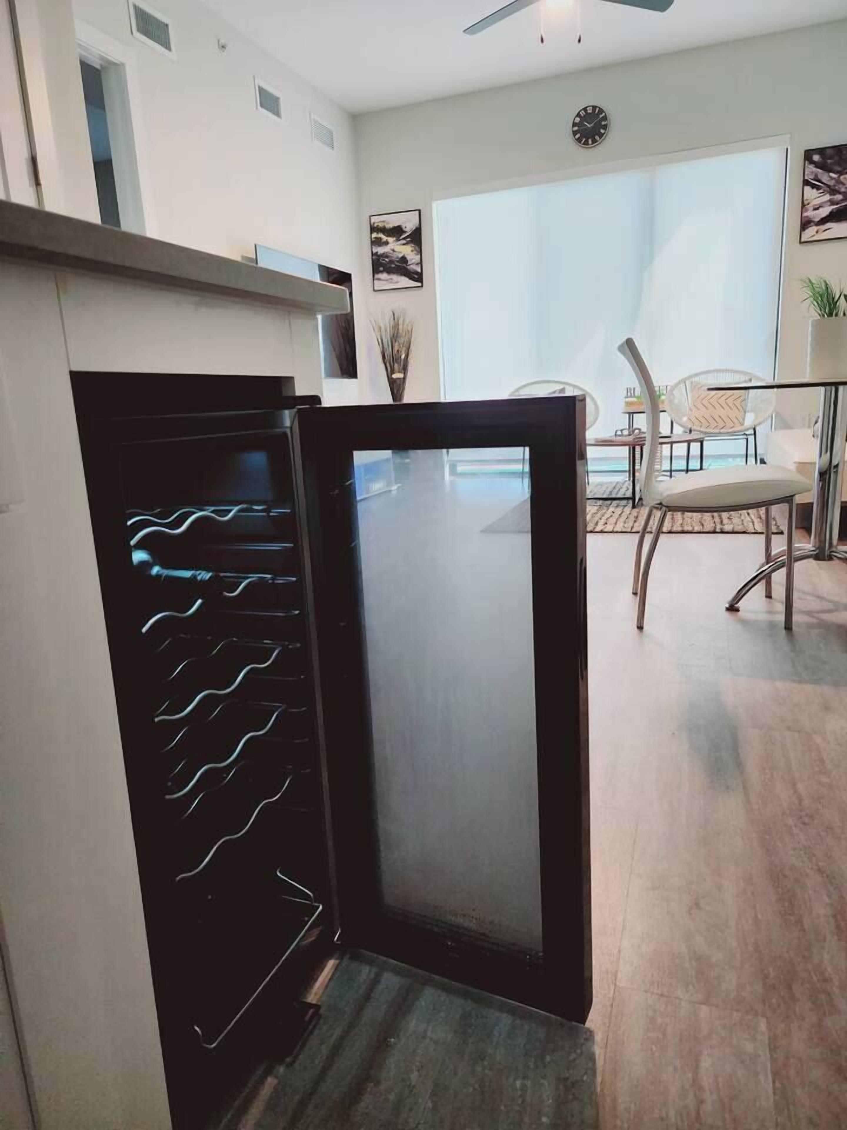 A modern kitchen with a black refrigerator, a dining area with chairs, and a large window.