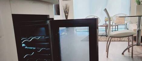 A modern kitchen with a black refrigerator, a dining area with chairs, and a large window.