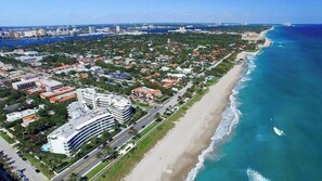 Vista aérea de uma cidade costeira, com um hotel em destaque e um estacionamento.