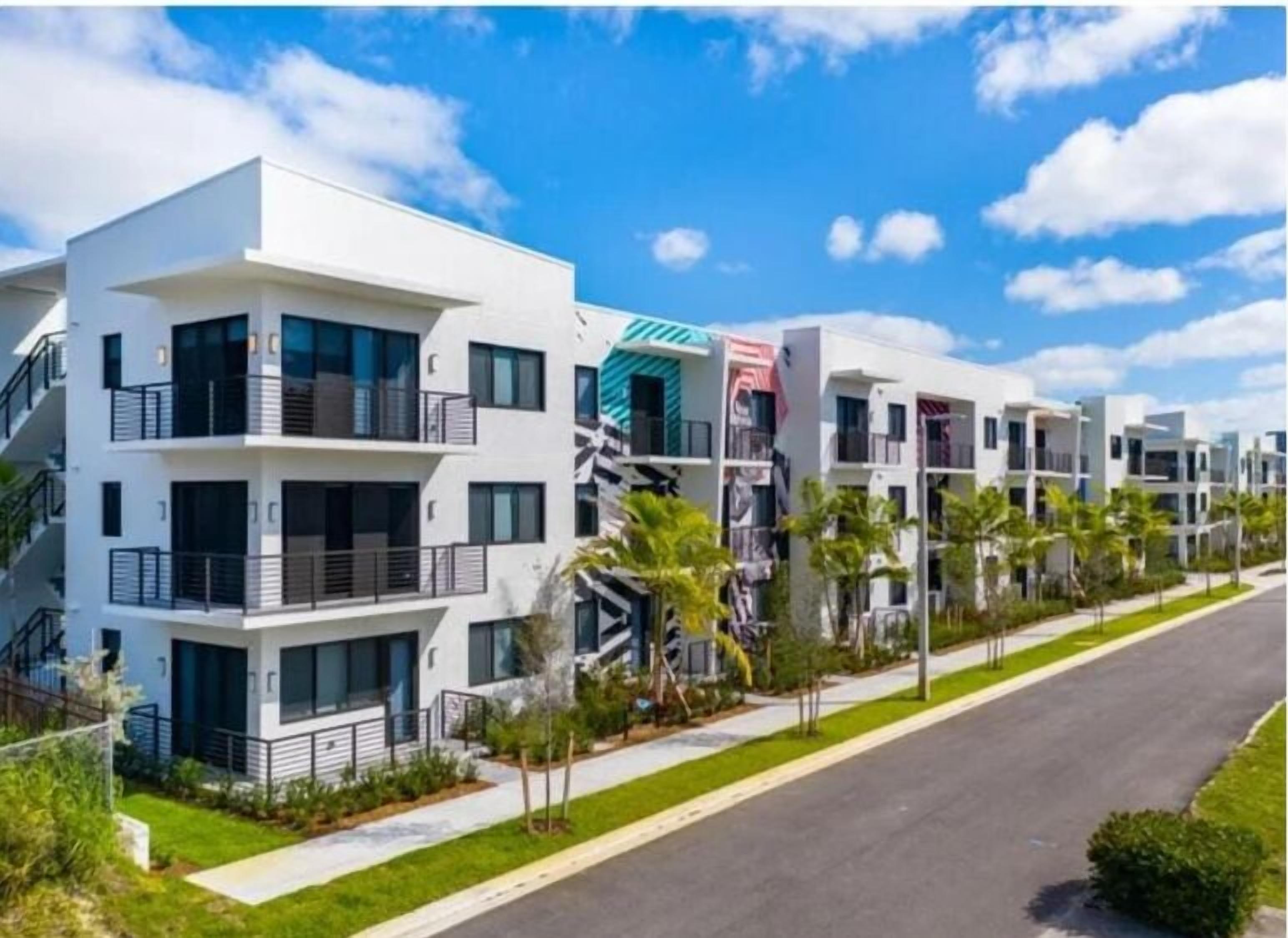 A modern multi-story residential building with balconies and a street view.