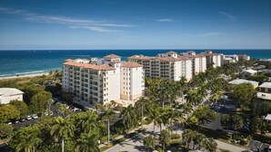 A beachfront hotel with multiple buildings, a parking area, and palm trees. - Singer Island | Coastal Escape | Pools & Beach Days (Palm Beach Shores)