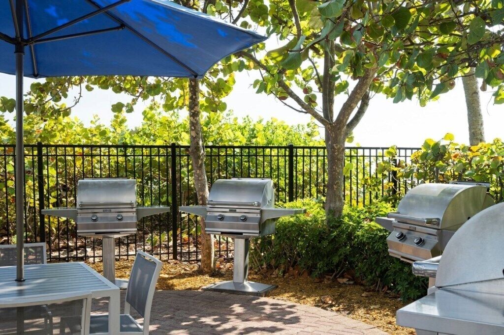 An outdoor patio with a grill, a table, and an umbrella.