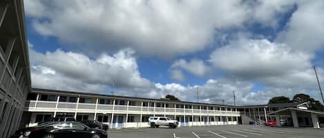 A motel with a parking lot, a covered area, and a building with multiple floors and balconies.