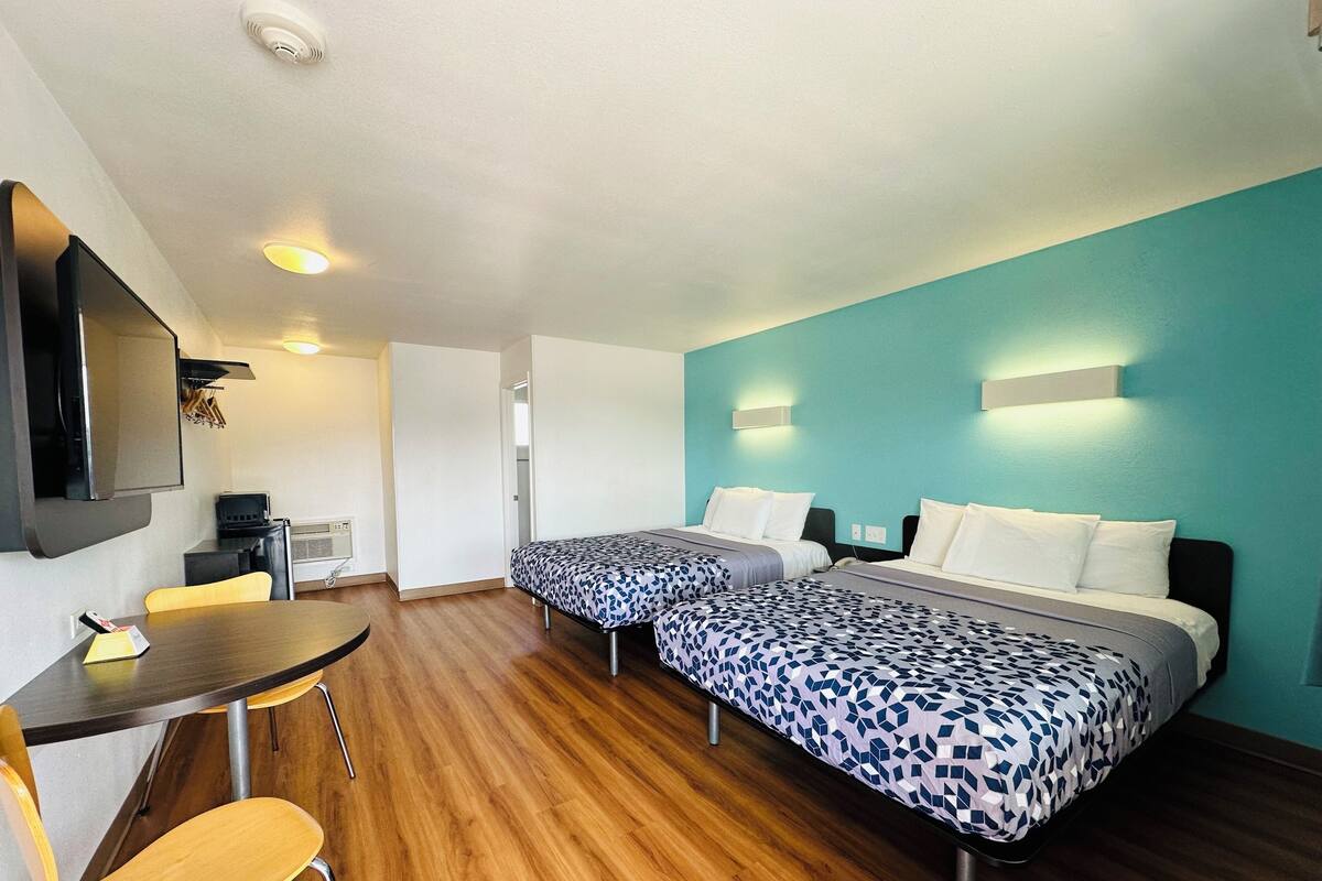 A hotel room with two beds, a desk, and a chair.