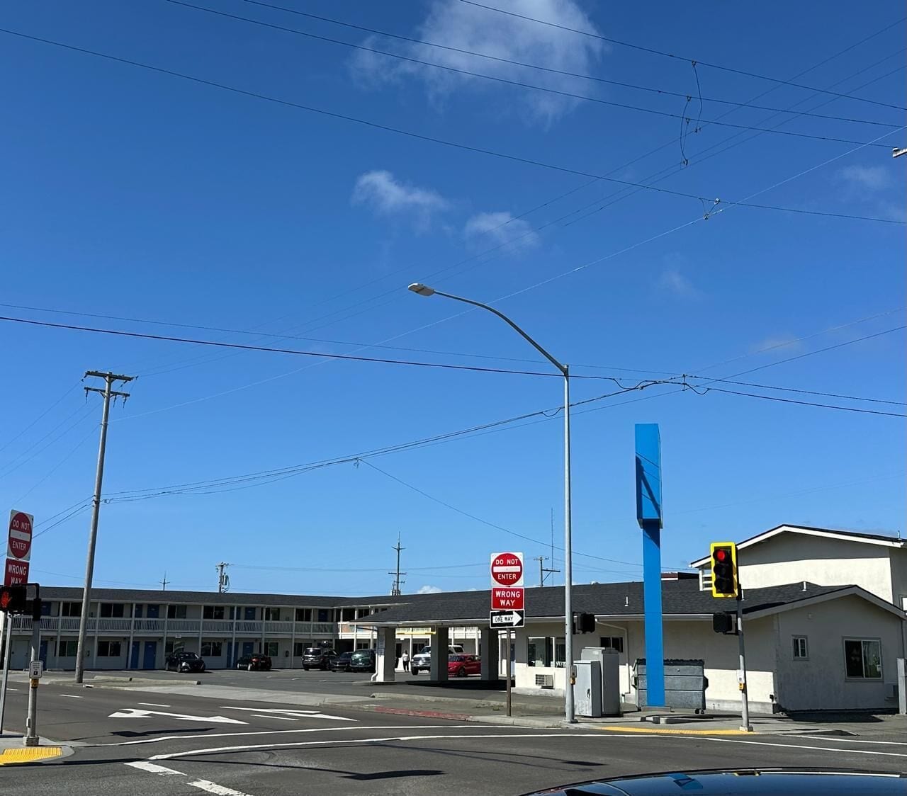 A gas station with a blue sign, a traffic light, and a 'Do Not Enter' sign.
