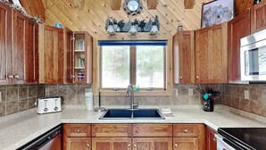 A kitchen with wooden cabinets, a stainless steel sink, a microwave, and a toaster. - Special Memories by Taylor Made Deep Creek (Swanton)
