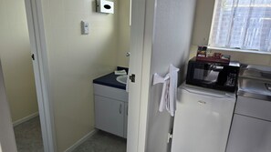 A compact kitchen with a microwave, refrigerator, and a small sink. - Marton Motel NZ (Marton)