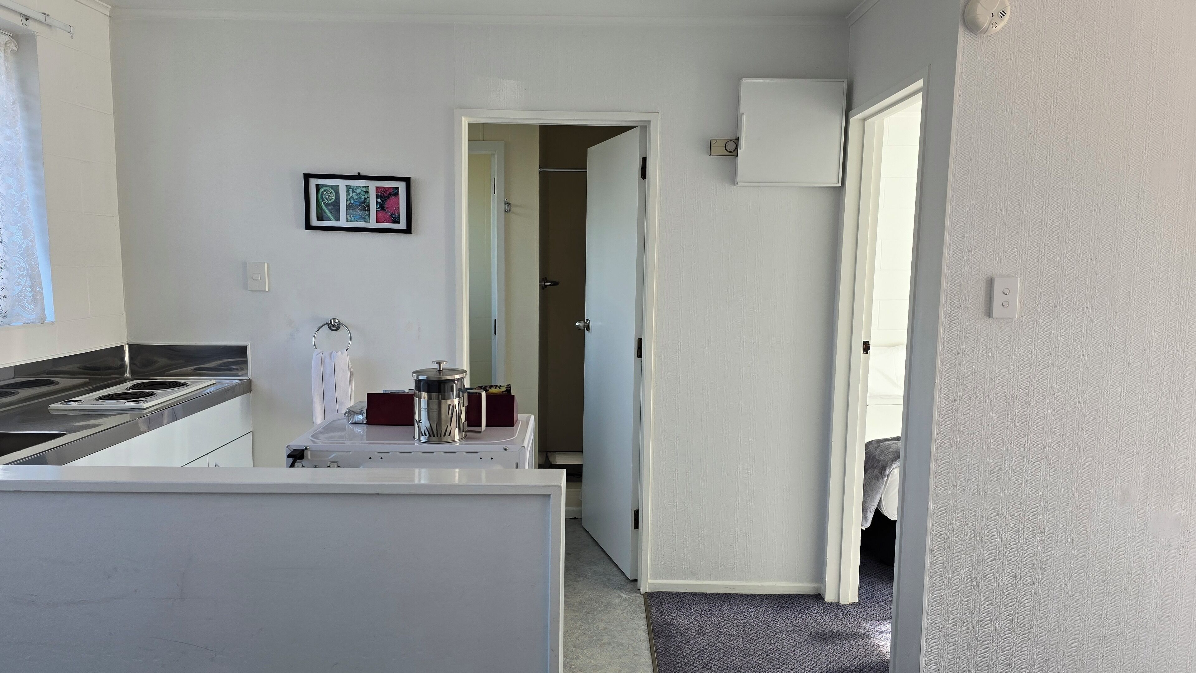 Une cuisine compacte comprenant une cuisinière, une petite table et une porte donnant sur un couloir.