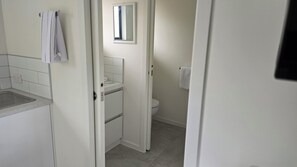 Un baño con inodoro, lavamanos y espejo.