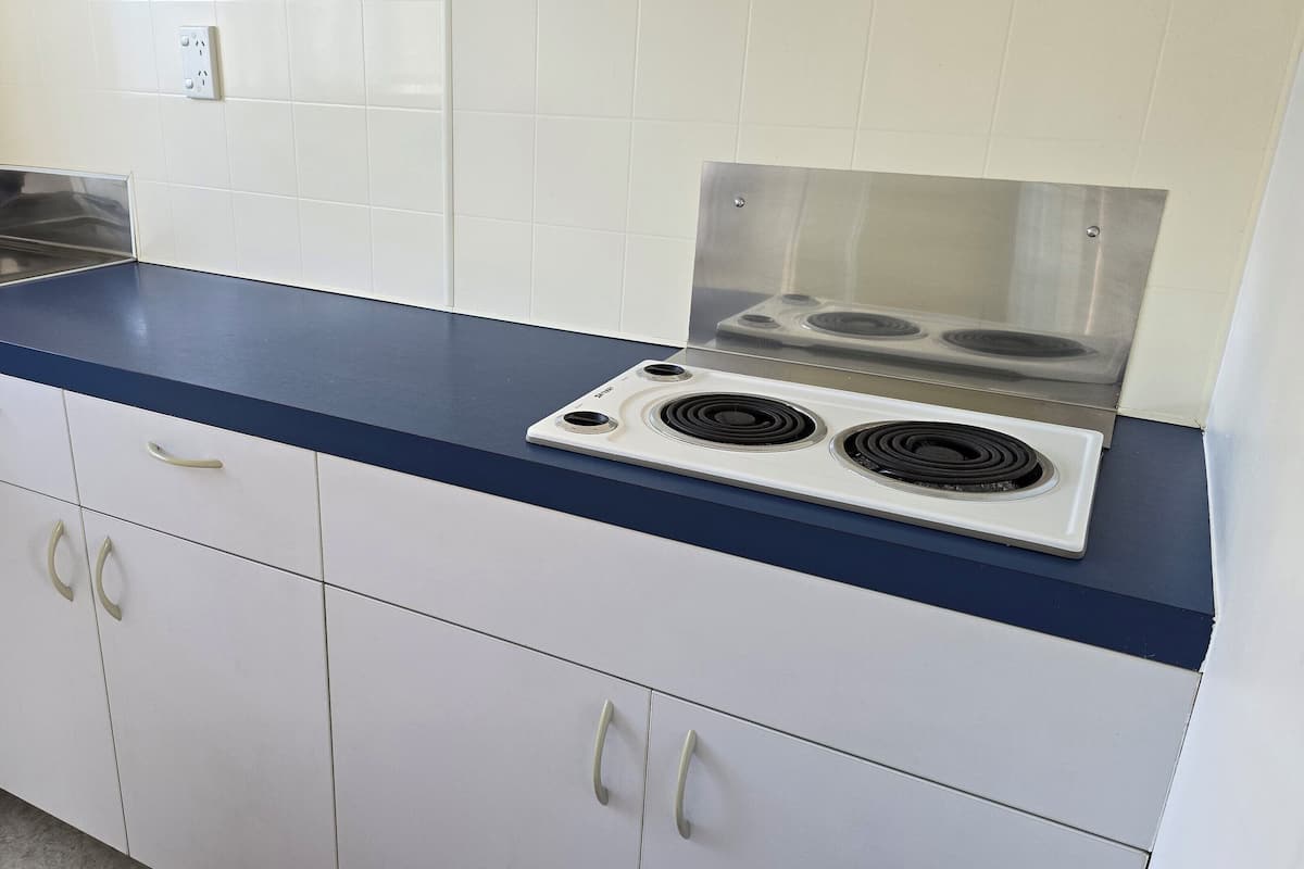 A kitchen with white cabinets, a blue countertop, and a built-in stove with two burners.
