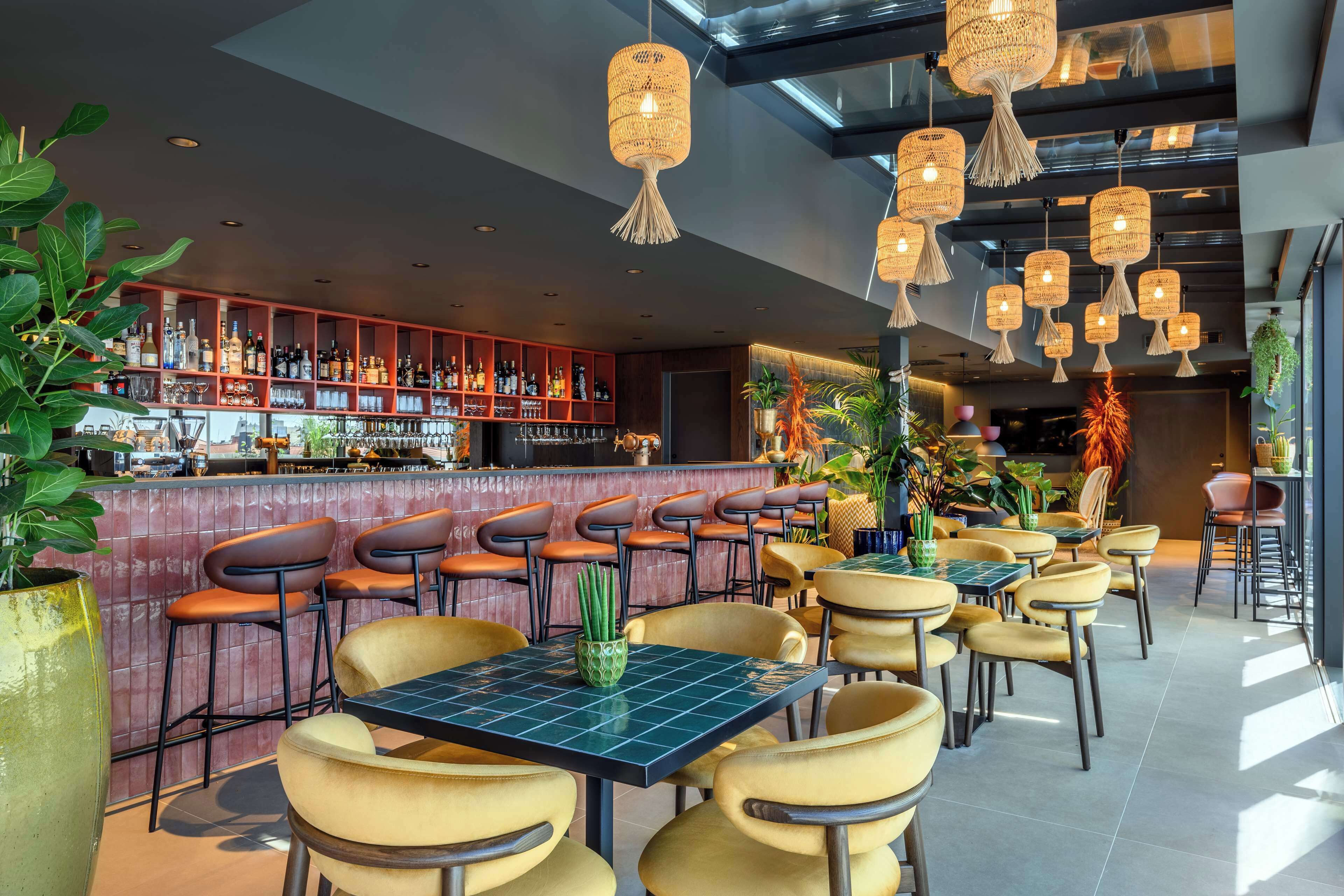 Ein Restaurant mit Barbereich, verschiedenen Sitzgelegenheiten und hängenden Korblampen.