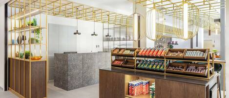 A modern interior with a wooden reception desk, a glass partition, and a display of snacks.