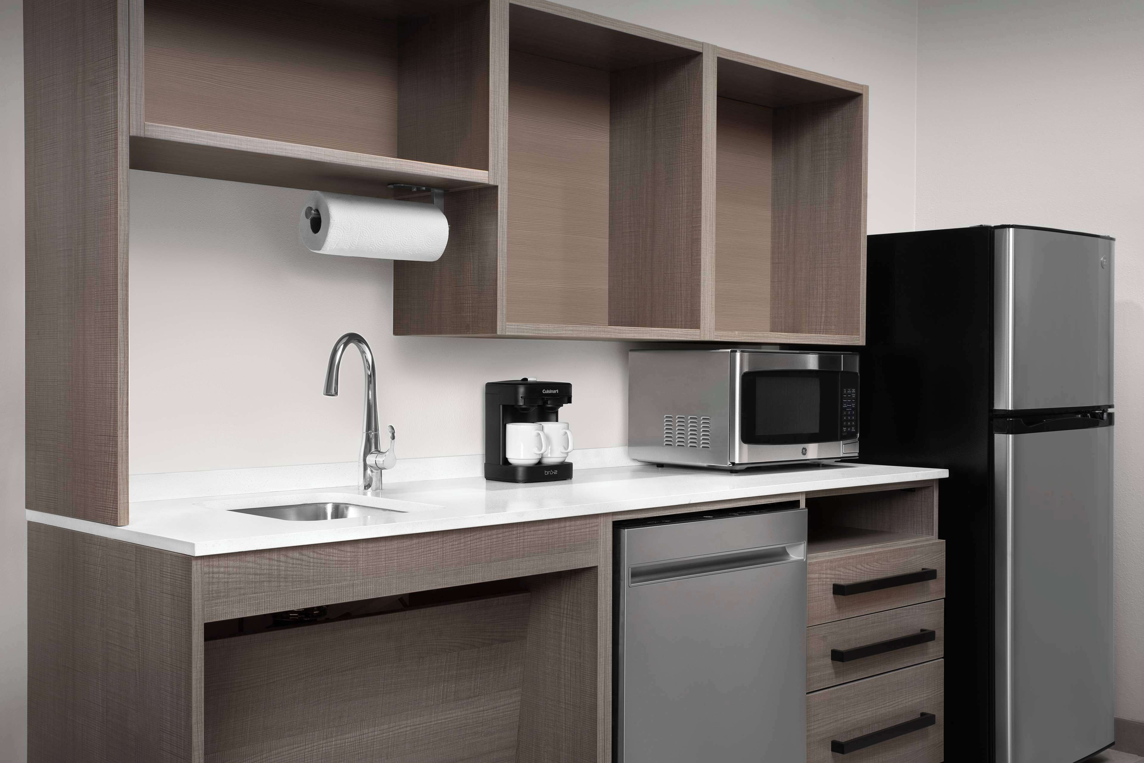 A modern kitchen with a stainless steel refrigerator, a built-in microwave, a coffee maker, and a dishwasher.