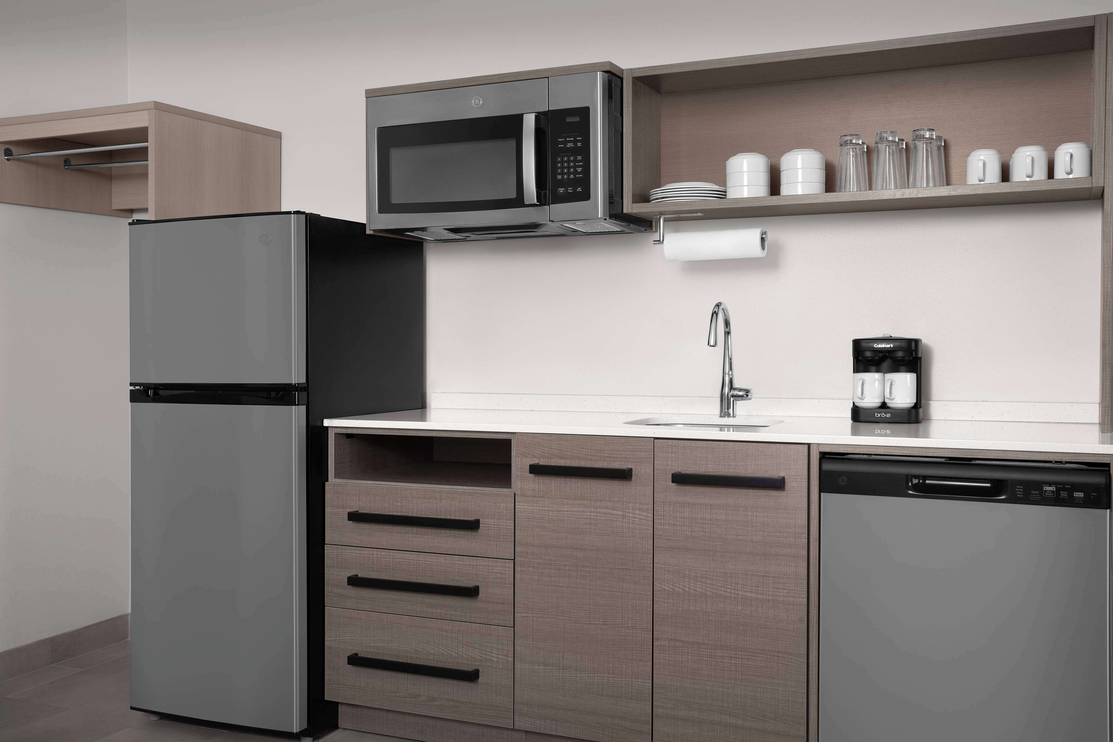 Una cocina compacta equipada con refrigerador, microondas, cafetera y lavavajillas.