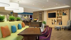 A modern living room with a sofa, dining table, purple chairs, a TV, and a kitchen area. - Home2 Suites By Hilton Athens I 65 (Athens)
