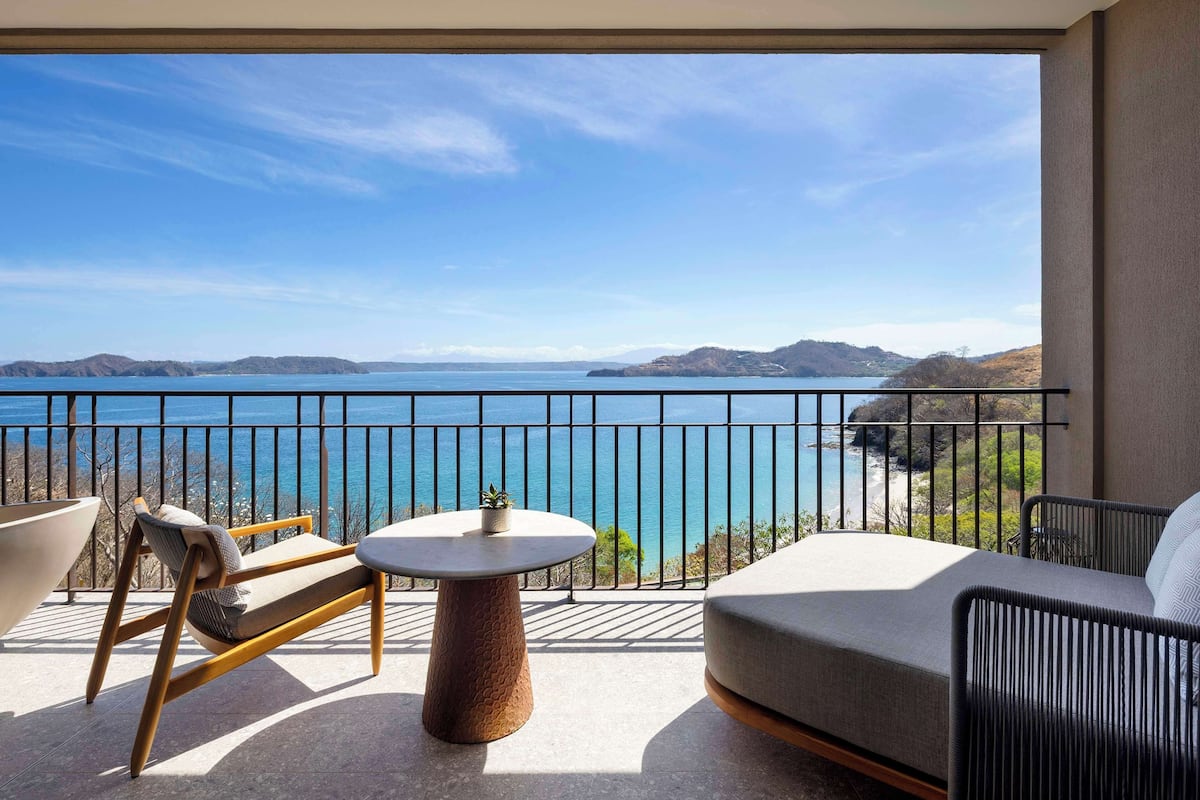 A balcony with a view of the sea, a round table, and a sofa.