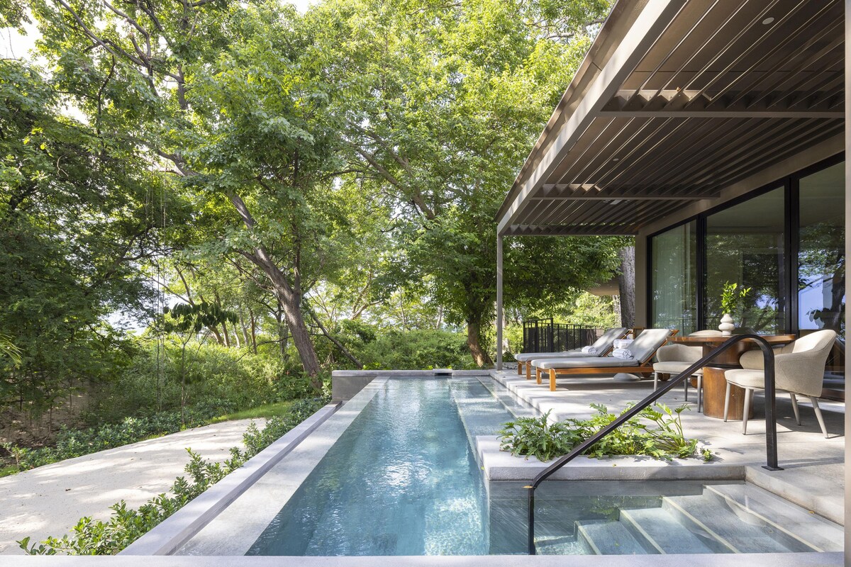 A modern outdoor pool area with lounge chairs and a pergola.