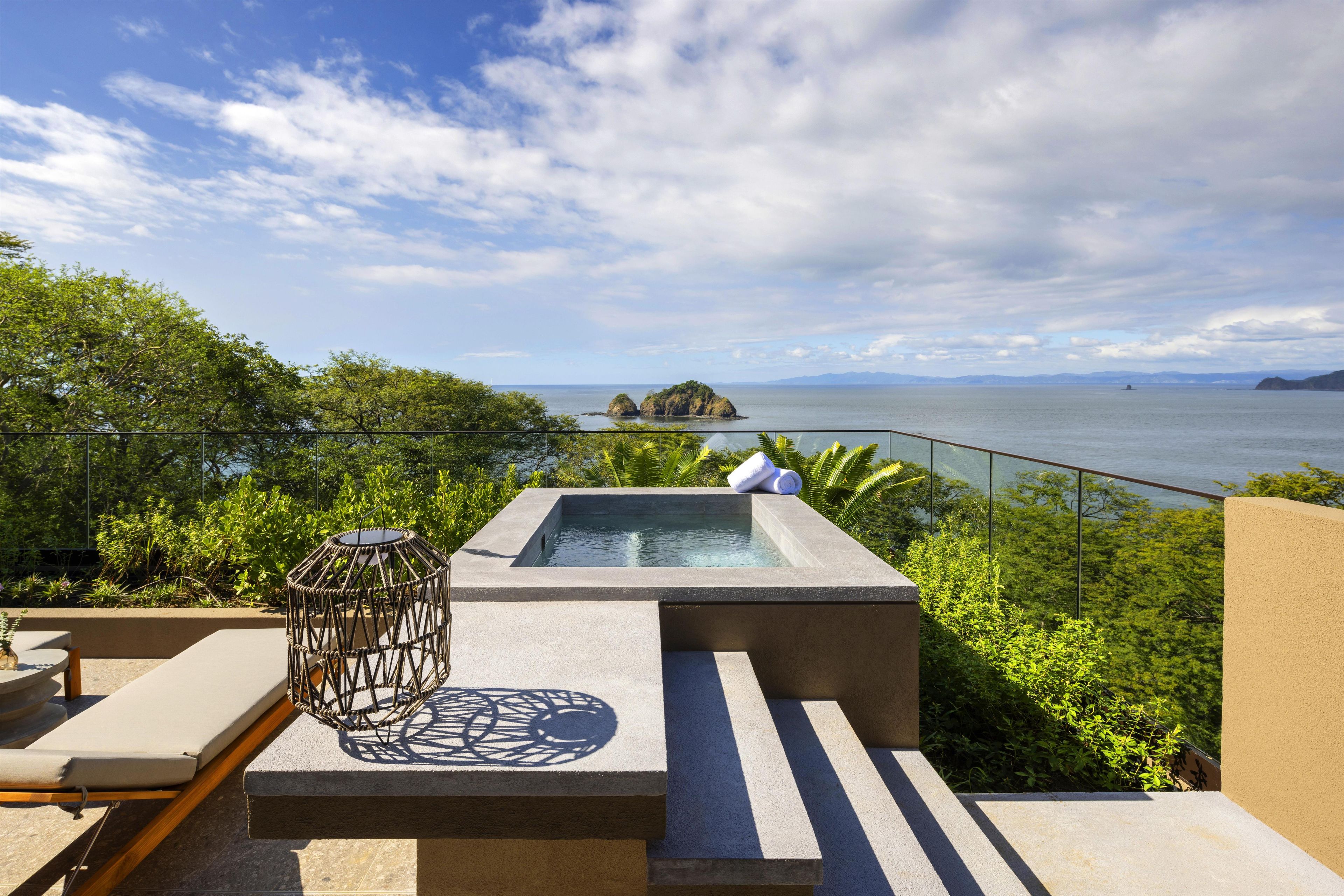 Una terraza en la azotea con jacuzzi, zona de estar y vistas al mar.