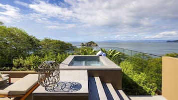 Una terraza en la azotea con jacuzzi, zona de estar y vistas al mar.