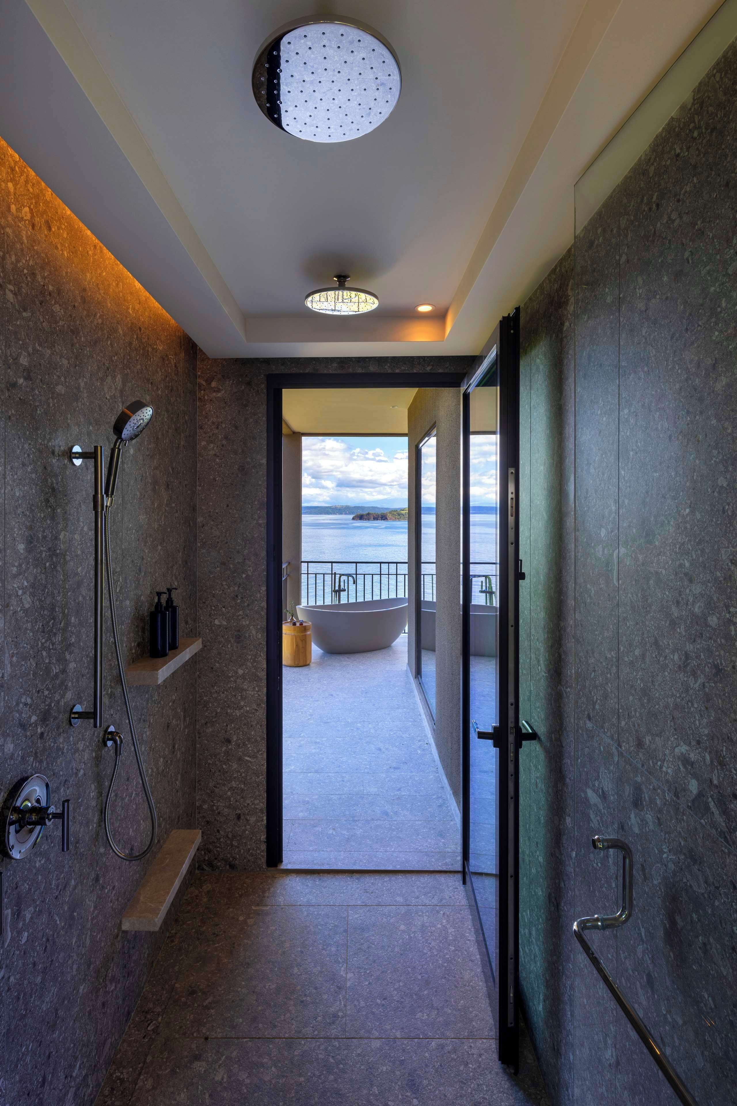 Un baño moderno con ducha, bañera y vista al mar.