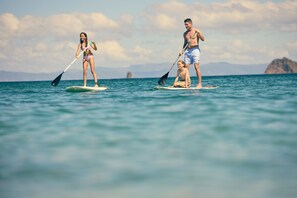 Three people on paddleboards in a body of water with a distant landmass. - Waldorf Astoria Costa Rica Punta Cacique (Sardinal)