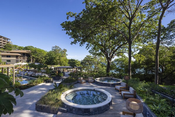 A rooftop pool area with hot tubs, lounge chairs, and a view of the surrounding buildings. - Waldorf Astoria Costa Rica Punta Cacique (Sardinal)