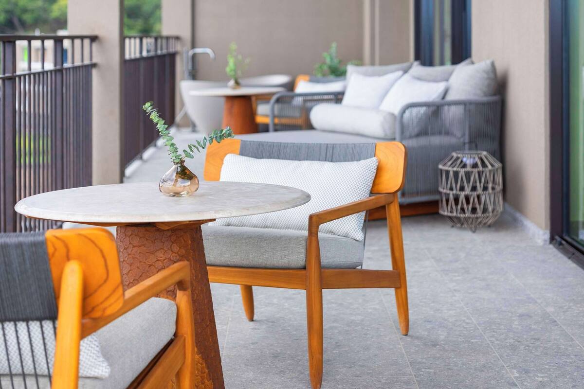 A balcony with a round table and two chairs, a sofa, and a small side table.
