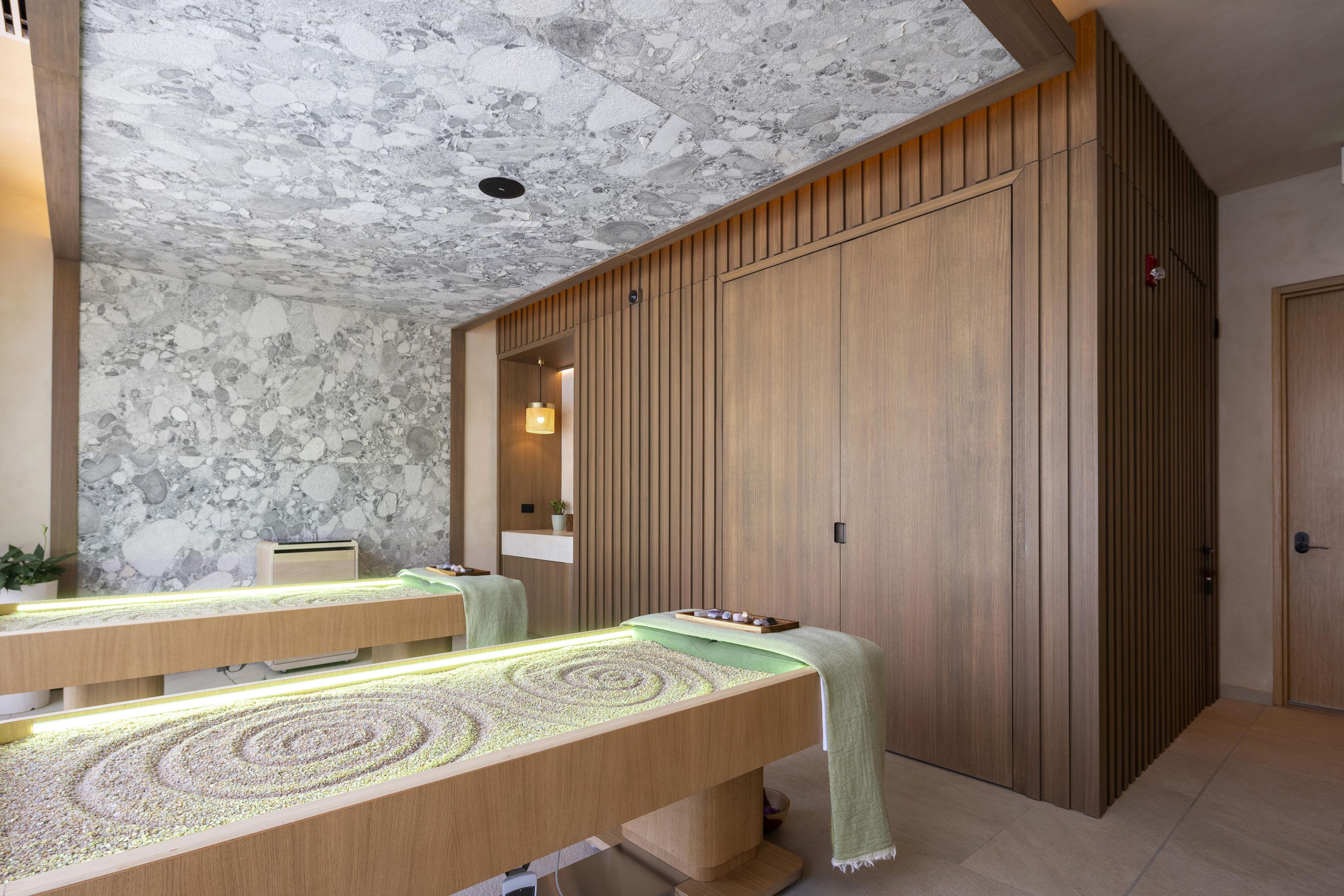 Un cuarto de spa con dos camillas, un armario de madera y una pared de piedra.