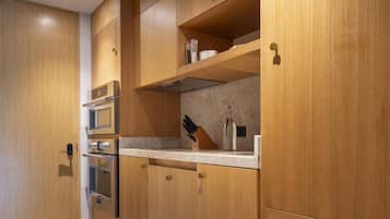 A modern kitchen with wooden cabinetry, stainless steel appliances, and a marble countertop.